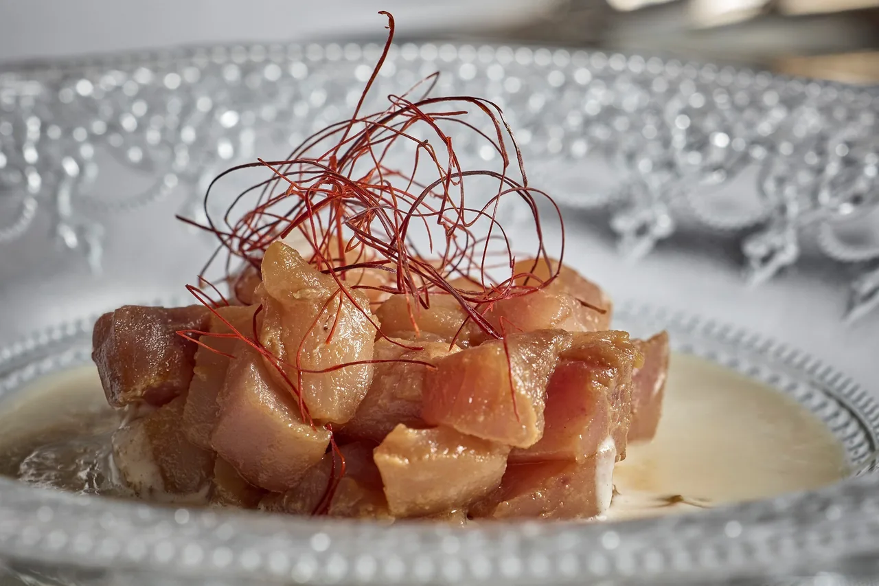 Pink diced fish with thin red threads on a decorative glass plate