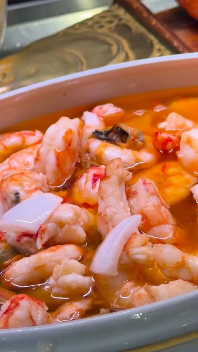 Close-up of a seafood dish with shrimp and langoustine tails in a light broth