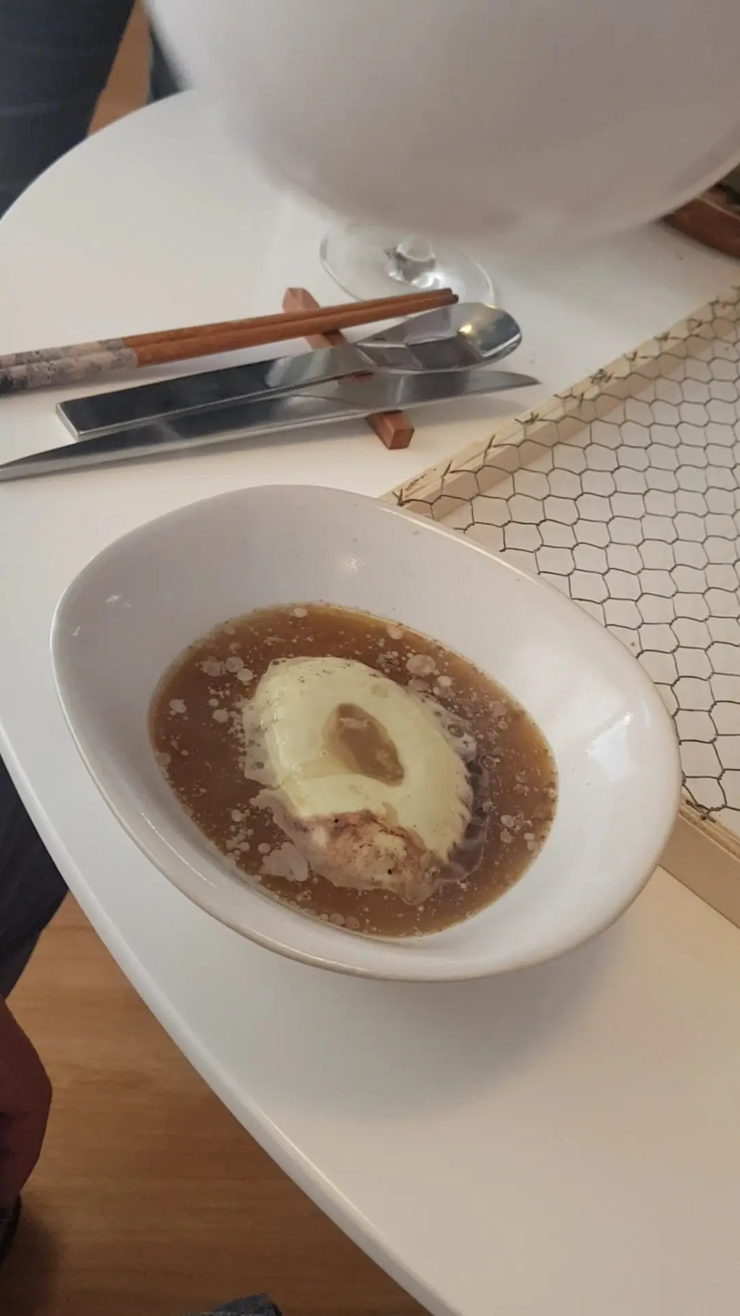Small white bowl with a poached quenelle in a clear broth, at L'Home dels Nassos.
