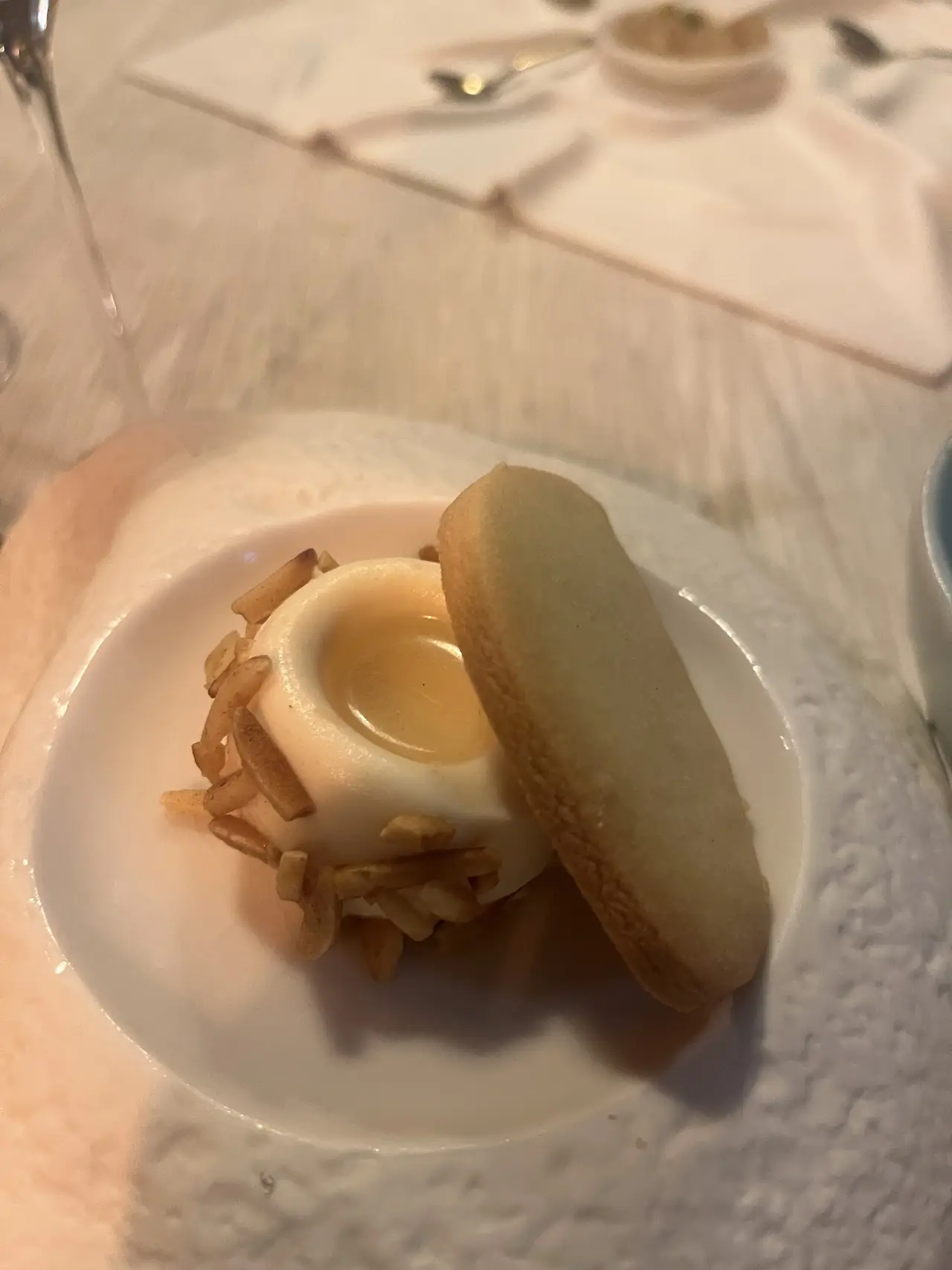 Cream-filled macaron-style dessert on a white plate, at L'Home dels Nassos.