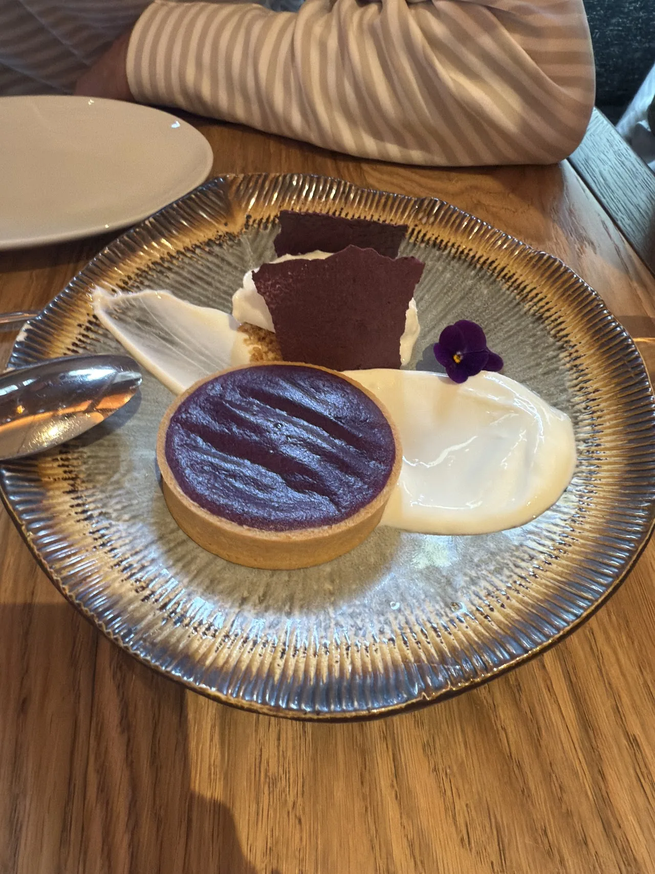 A dessert plate with a dark chocolate disc and cream