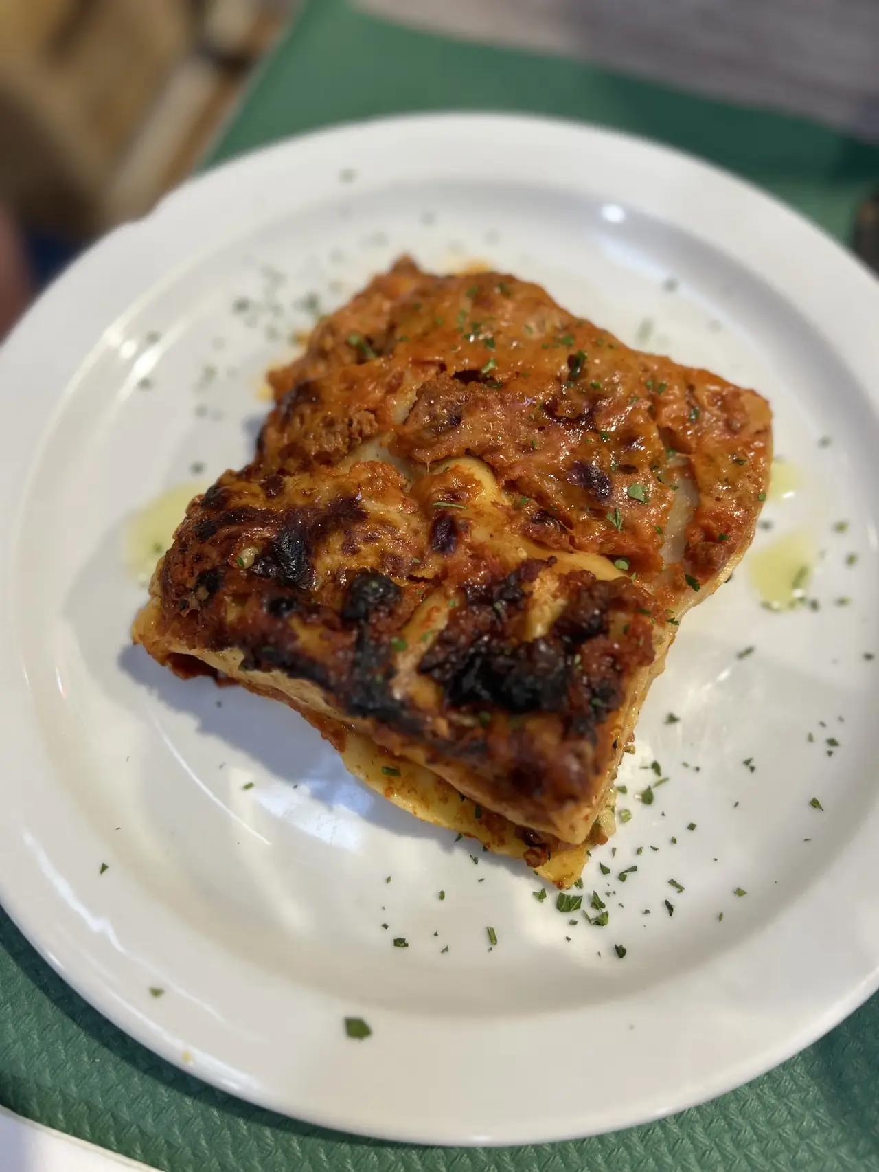 Overhead view of a slice of baked lasagna with herb garnish on a white plate