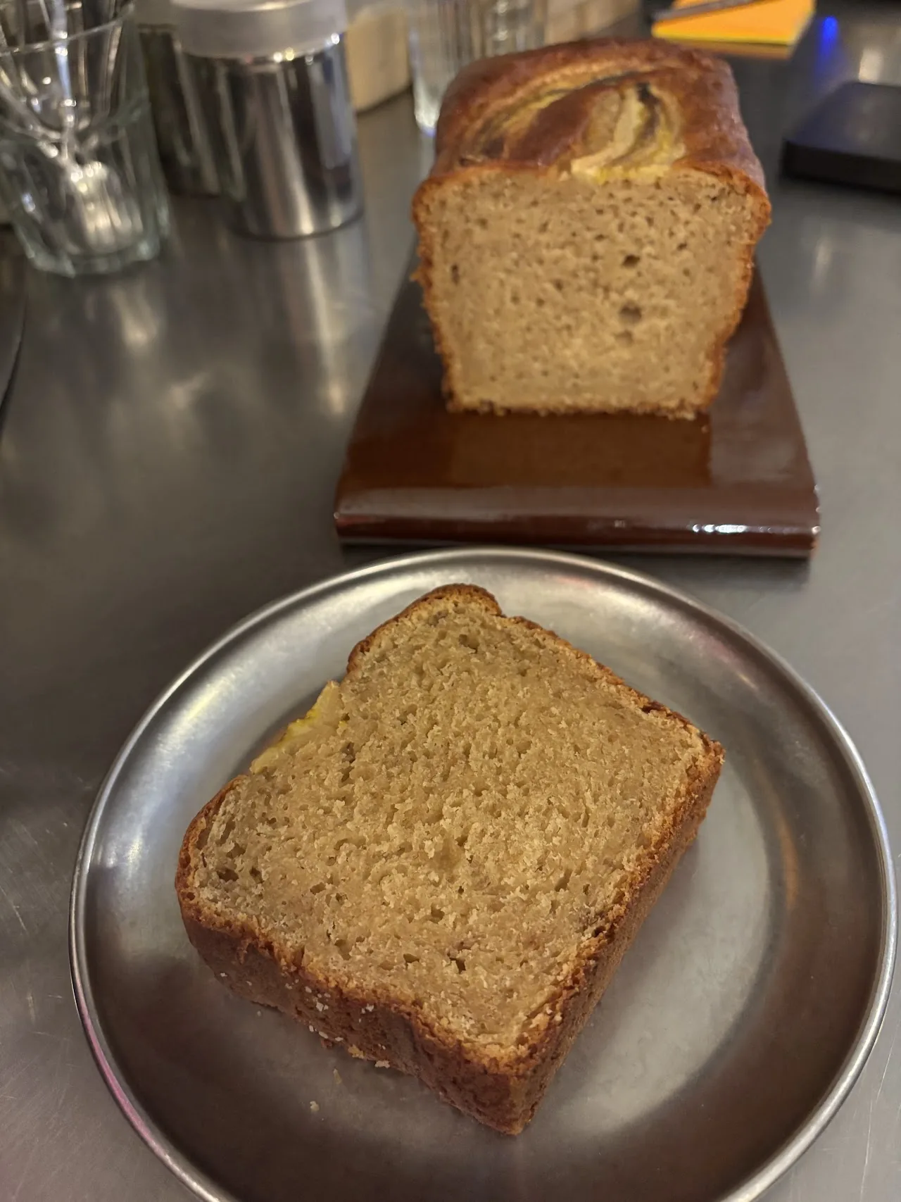 Slices of banana bread on a plate beside the loaf