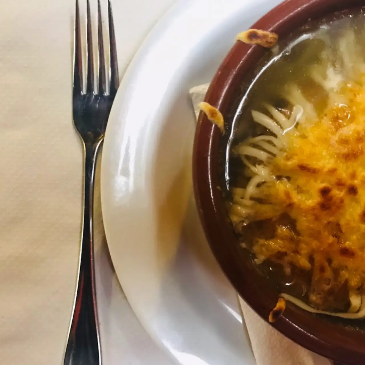 Baked onion soup topped with melted, browned cheese in a terracotta bowl at Restaurant La Llar de Foc