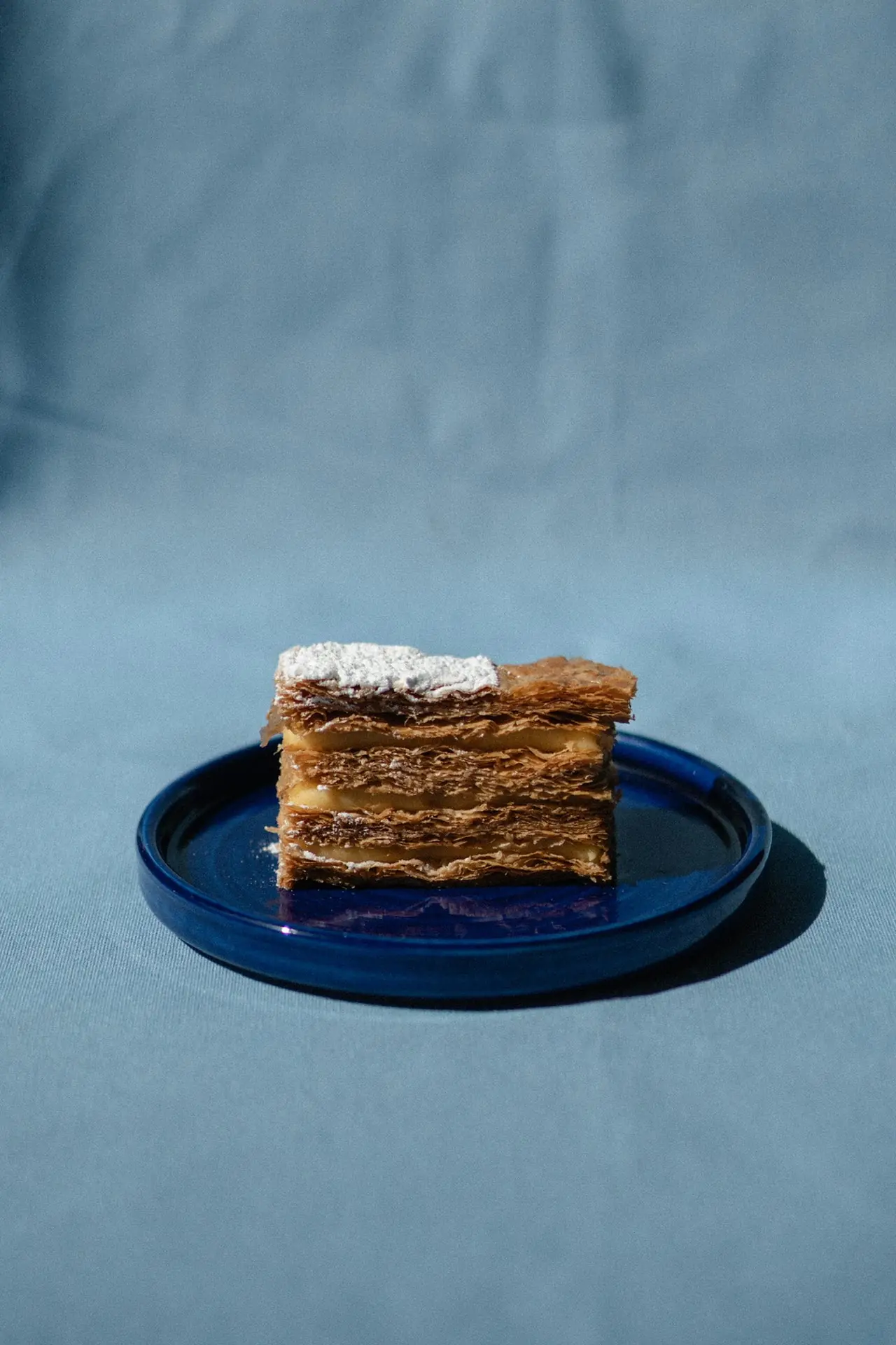 A slice of mille-feuille served on a blue plate