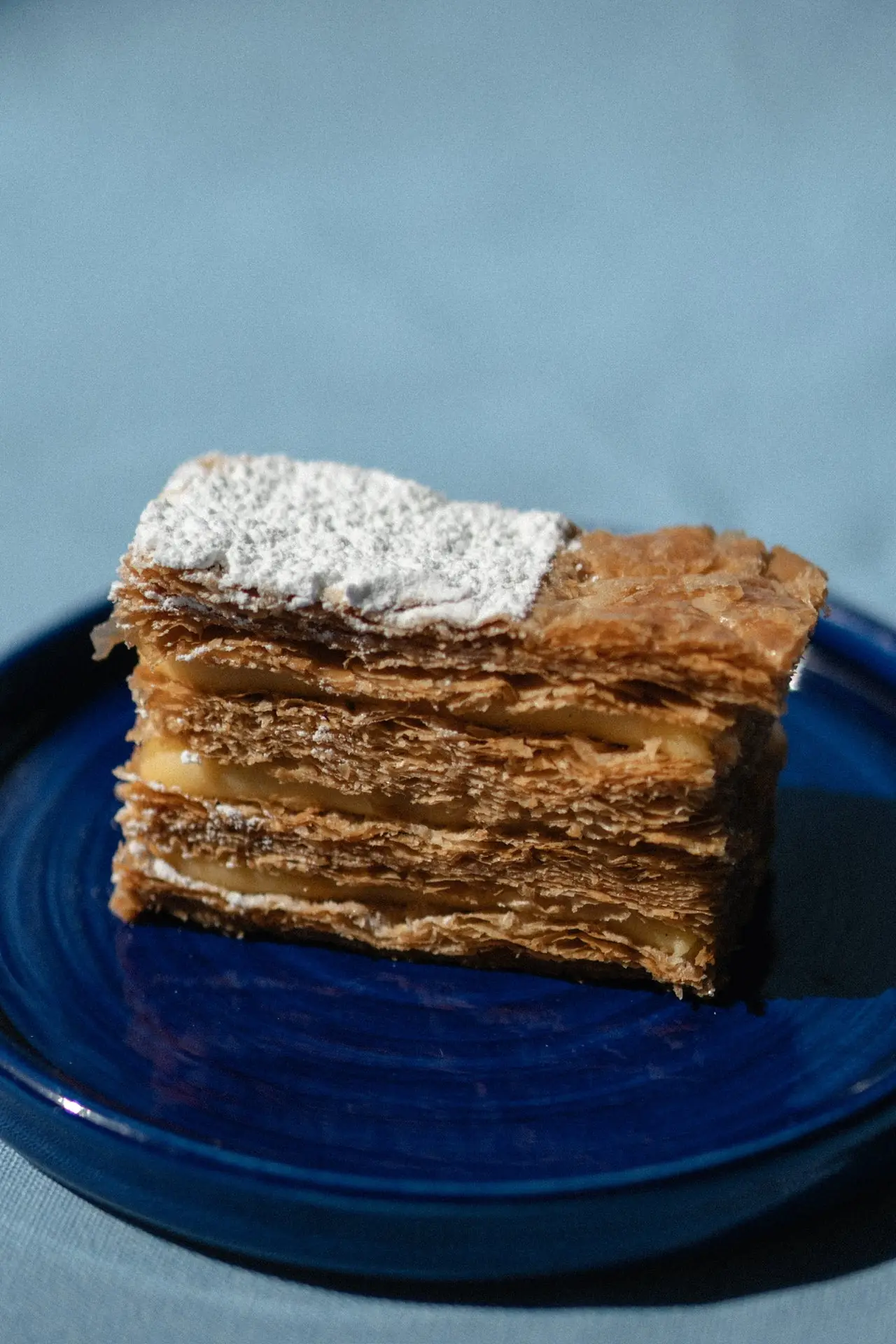 A mille-feuille with layered puff pastry and cream, dusted with icing sugar