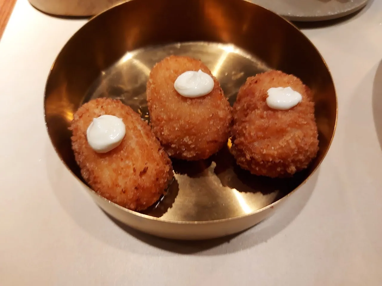 Three croquettes with a dollop of sauce in a metal bowl