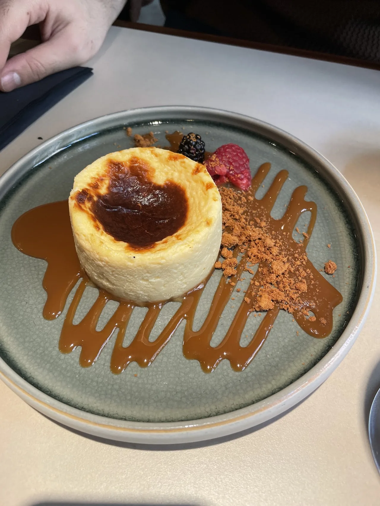 A slice of cheesecake with berry and caramel drizzle
