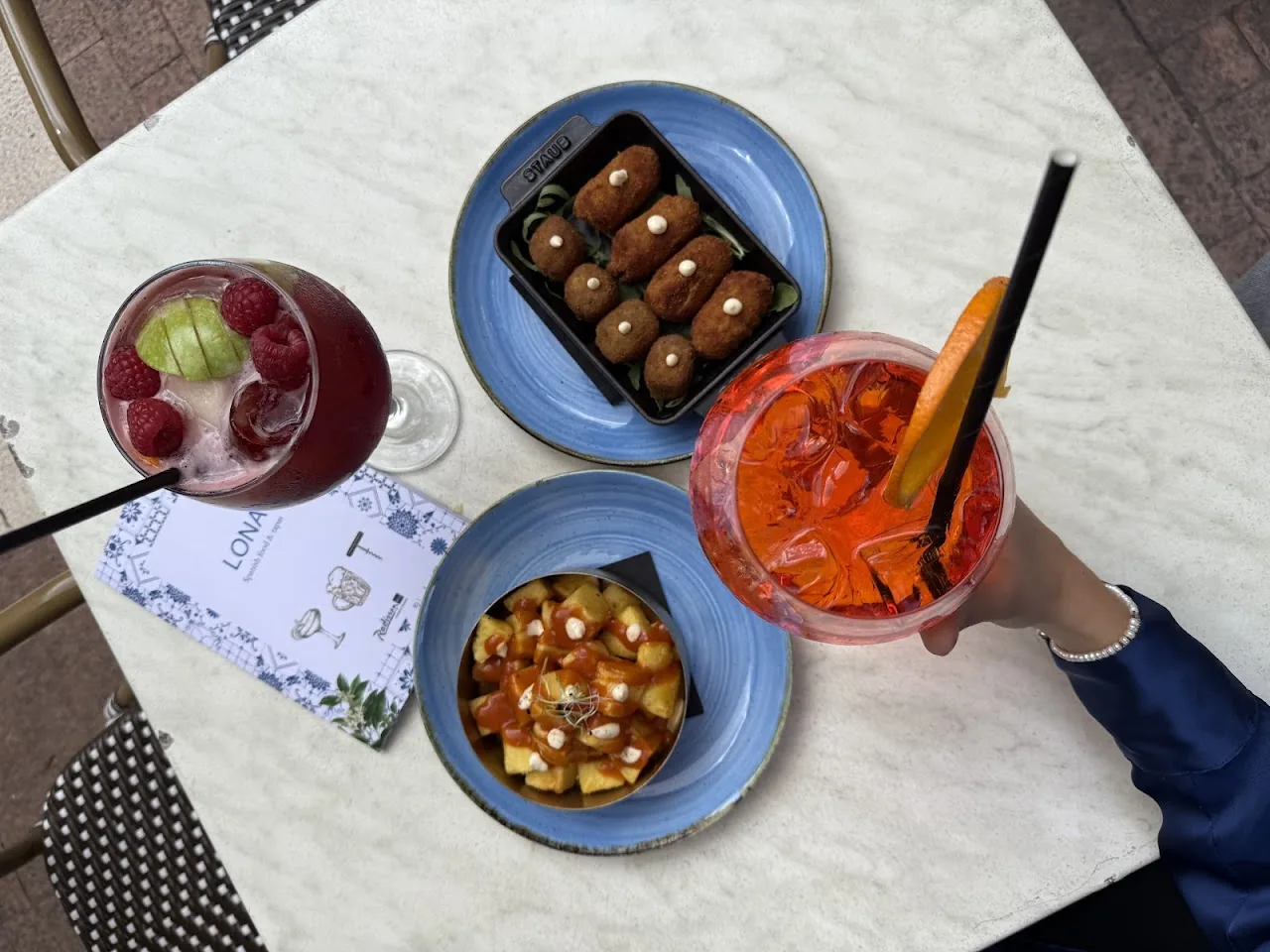 An overhead view of two cocktails and small tapas plates on a table