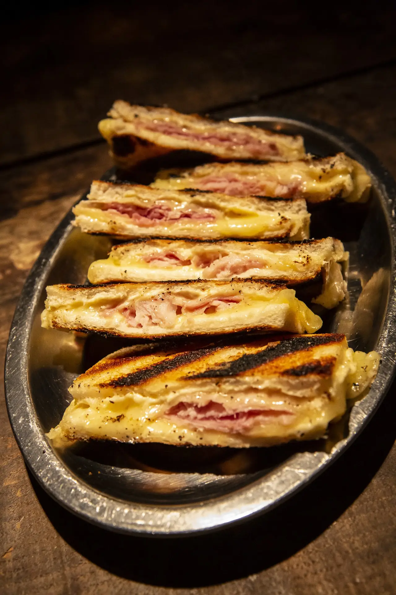 Grilled ham and cheese sandwich sliced into pieces on a metal plate