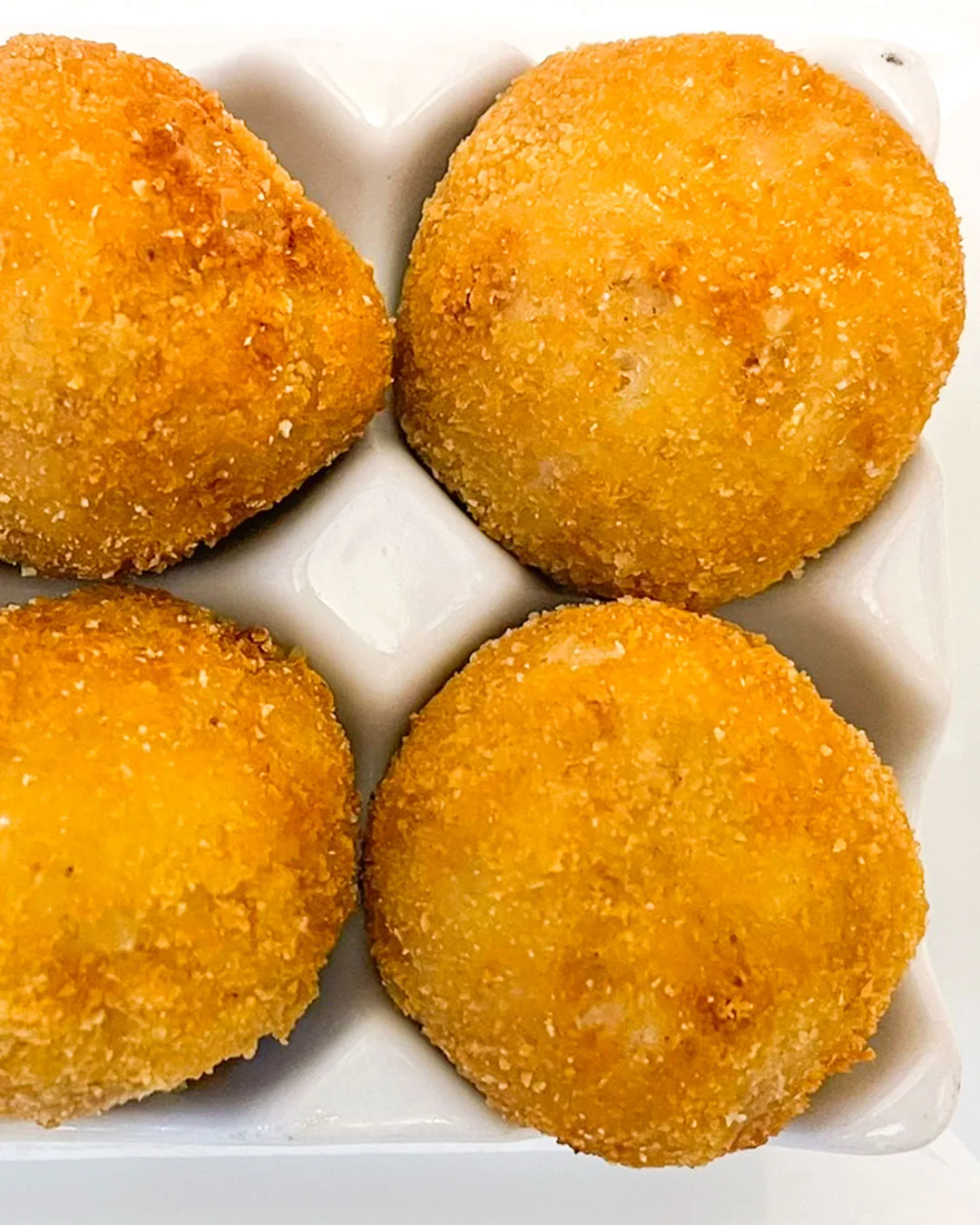 Four breaded croquettes on a plate