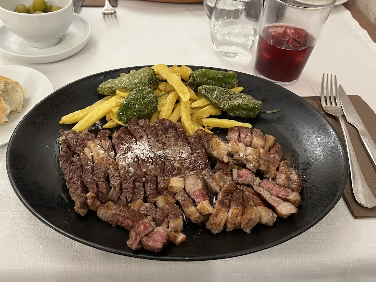 A grilled steak with fries and roasted peppers