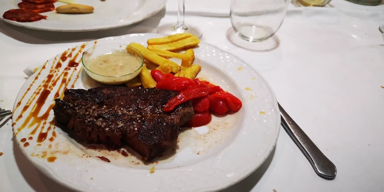A grilled steak with fries and roasted red pepper