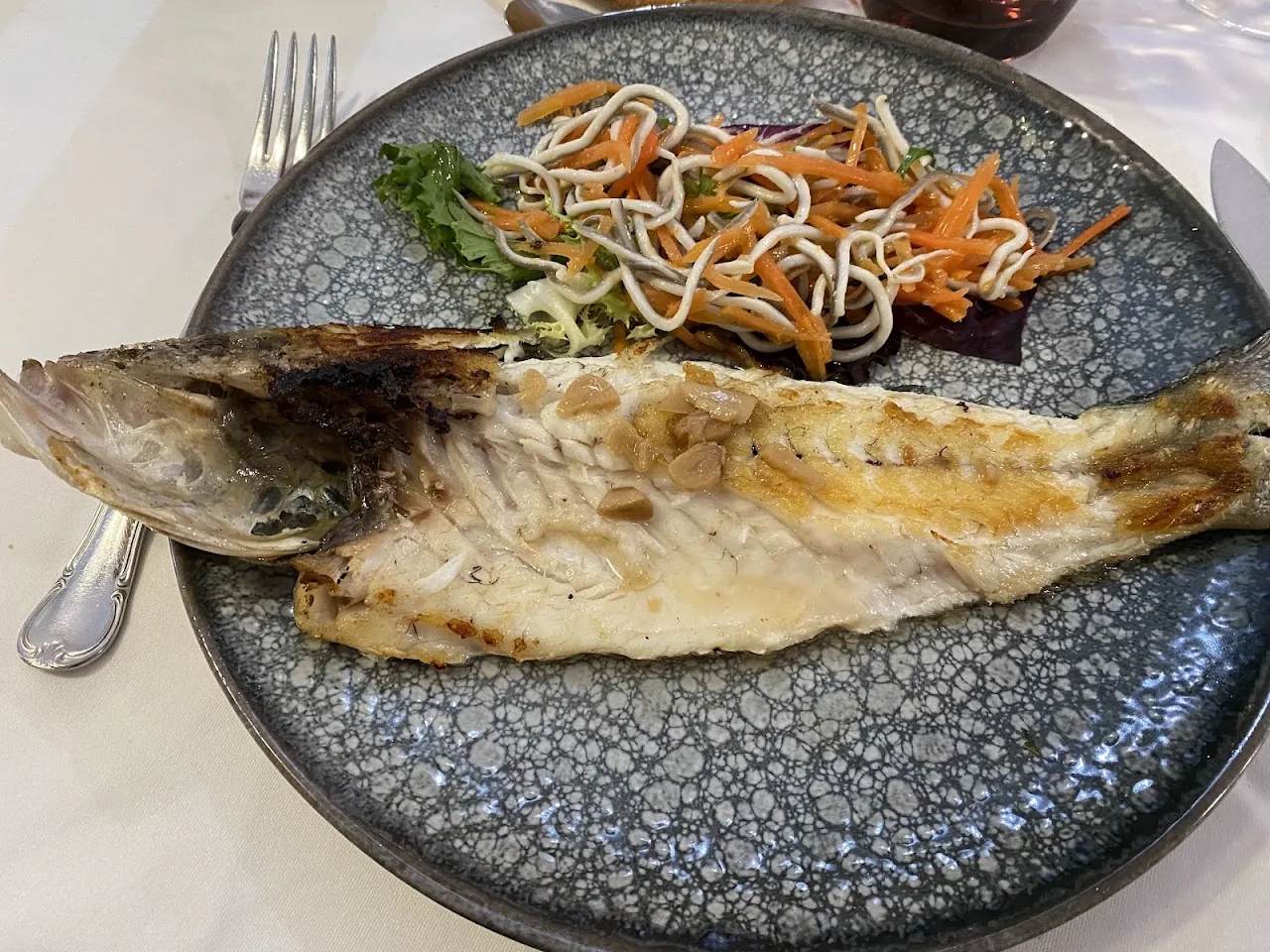 A whole grilled fish served with a noodle salad