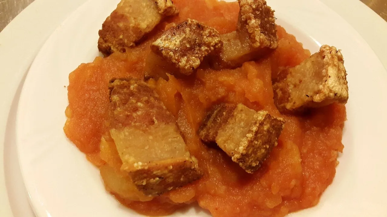 Golden fried pieces sitting on an orange purée on a white plate