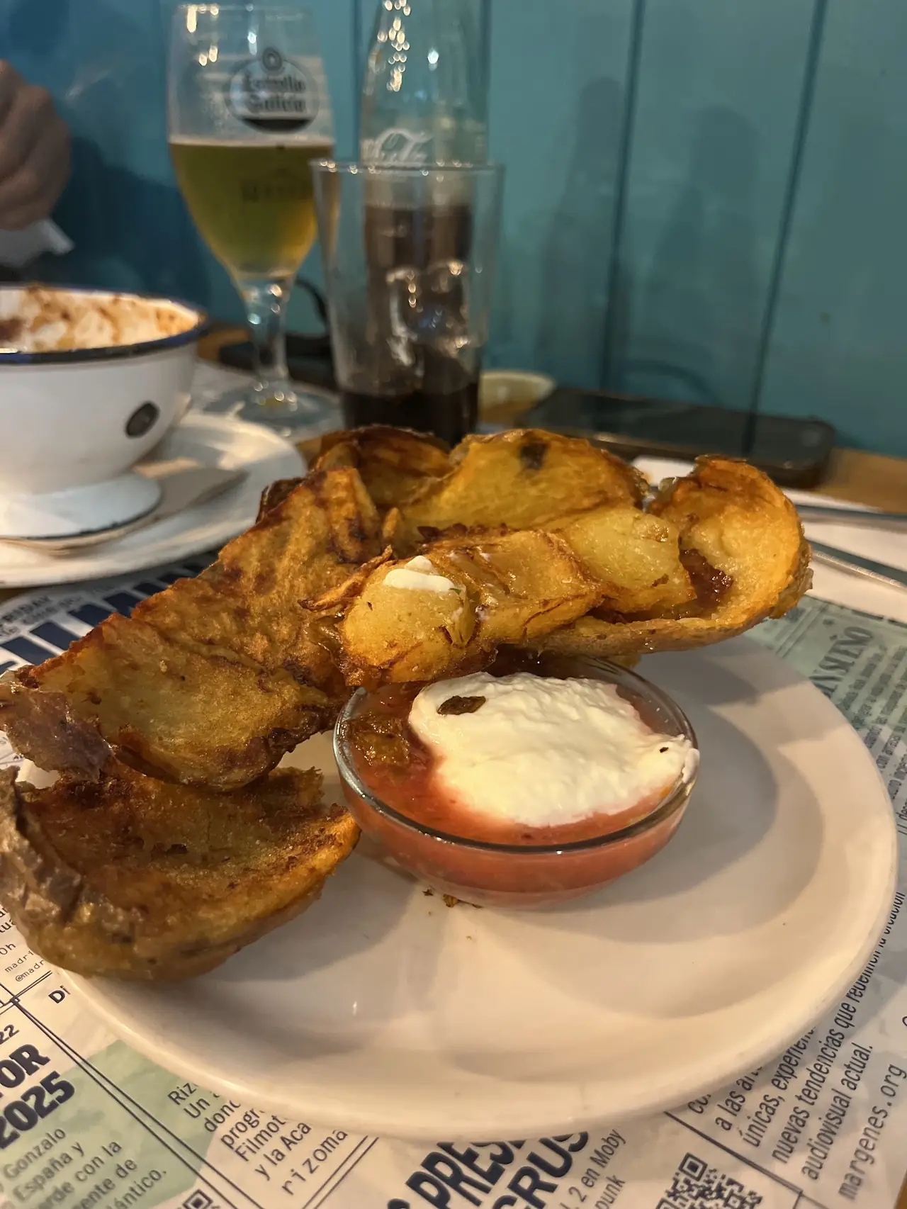 Fried potato wedges served with a small dish of cream and tomato sauce