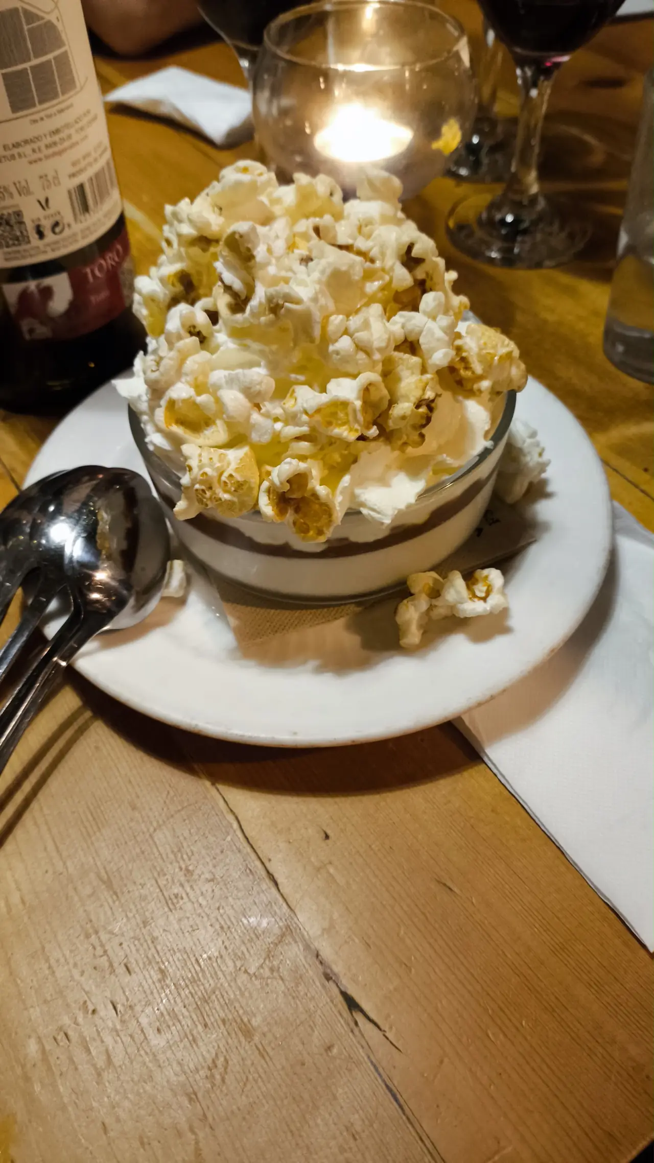Layered cream dessert topped with buttered popcorn, served table-side by candlelight