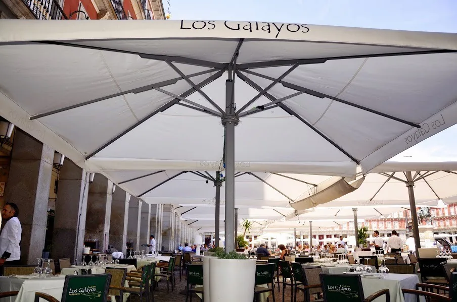 Large white parasols over terrace tables on a arcaded square