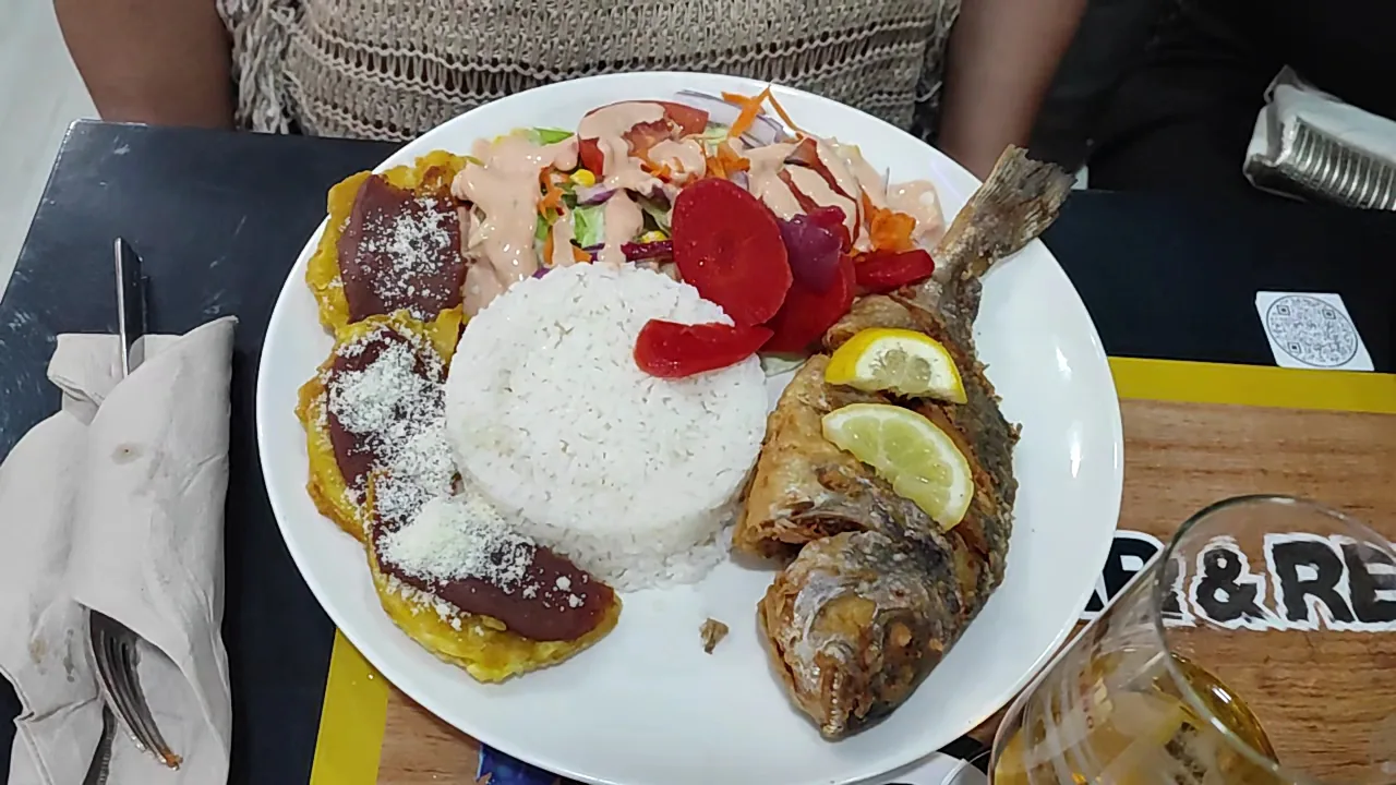A whole fried fish served with rice and plantain