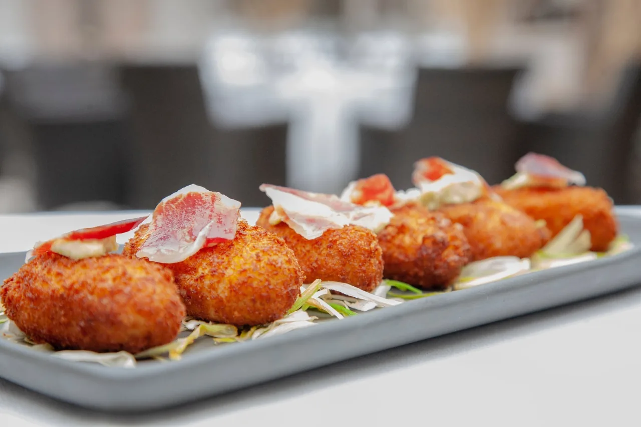 Golden croquettes on a long grey plate with a garnish of leaves