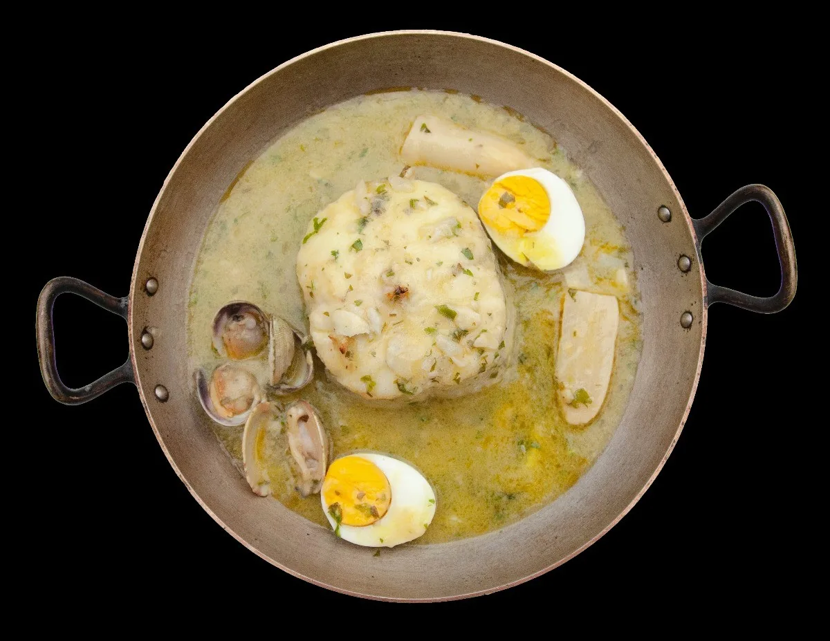 A pan of fish and clams in green sauce with boiled egg halves