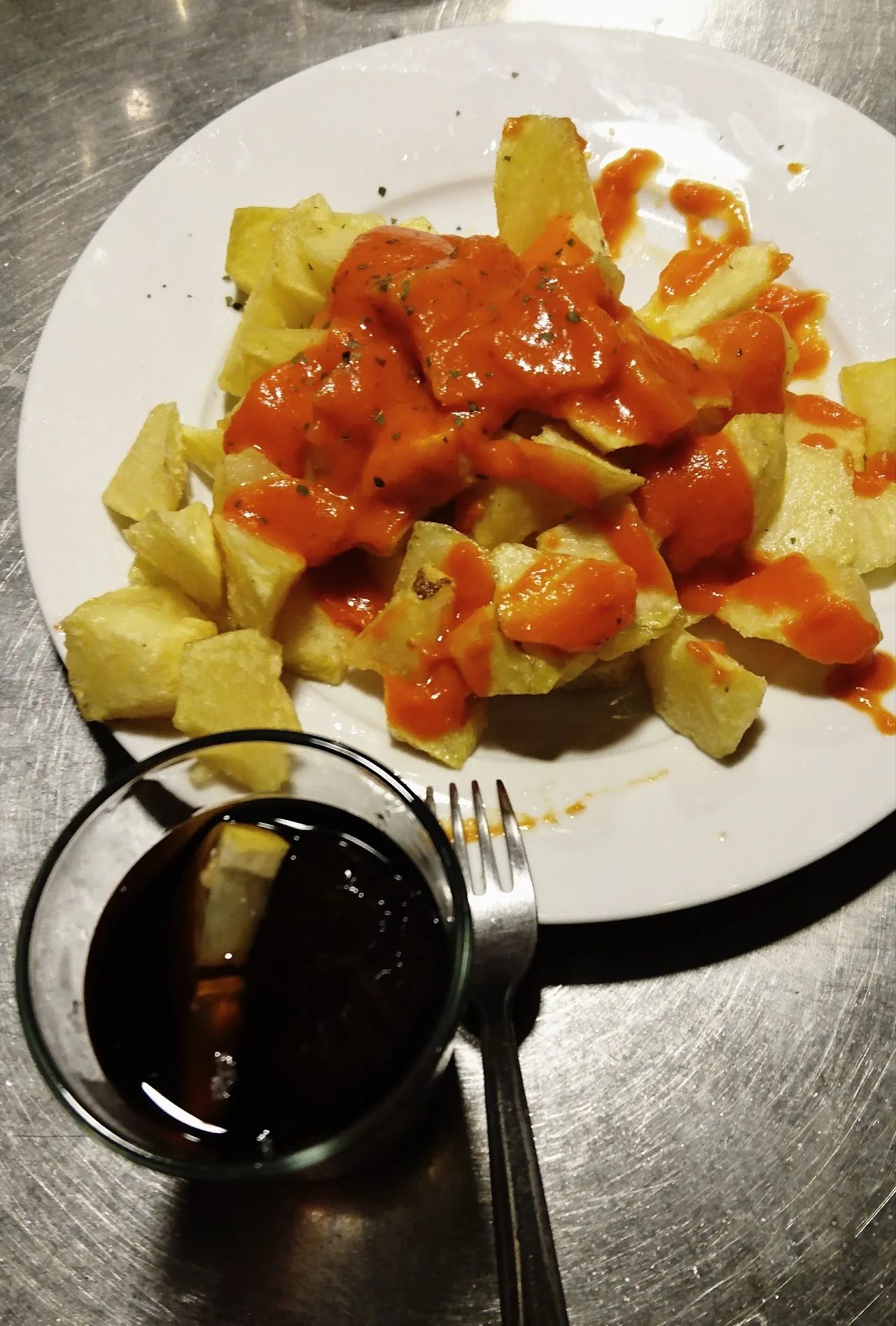 Fried potatoes in tomato sauce with a side dip
