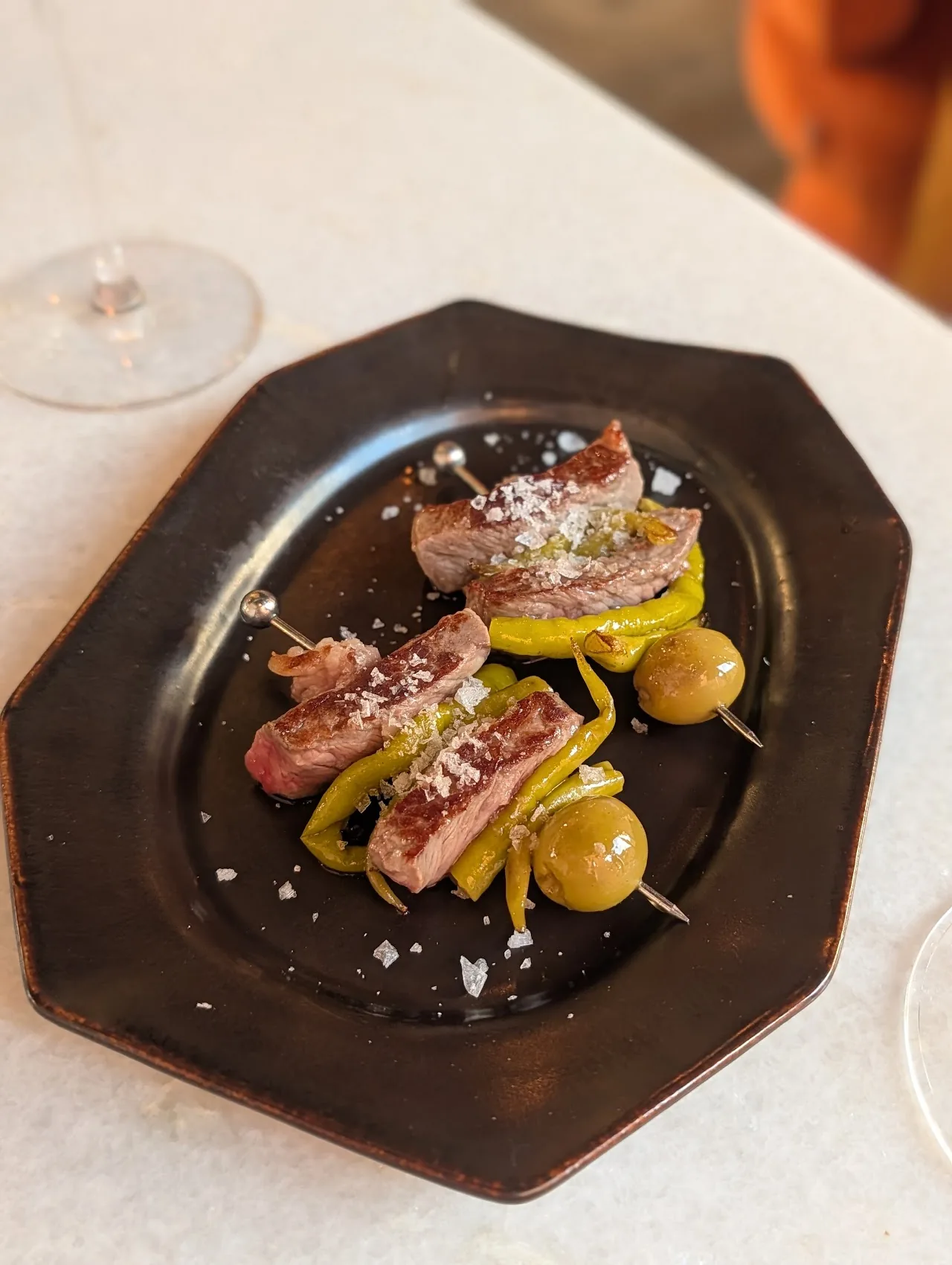 Tuna skewers with olives on a dark plate