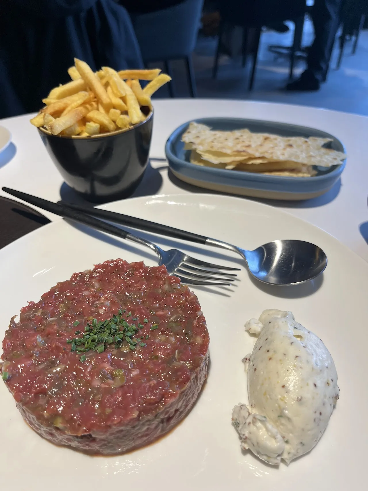 A steak tartare with a side of fries and sauce