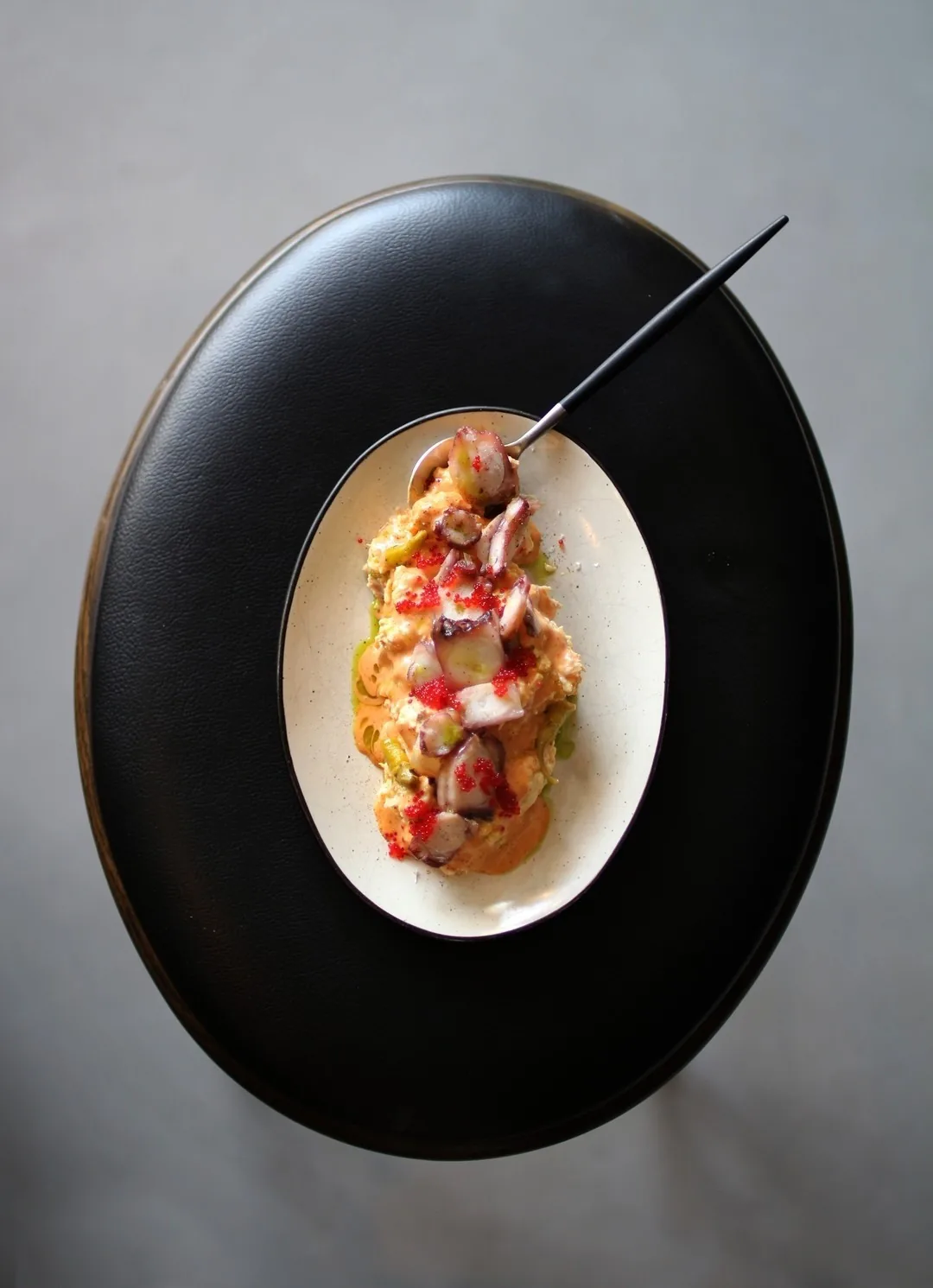 Pieces of octopus with red roe on a creamy orange sauce