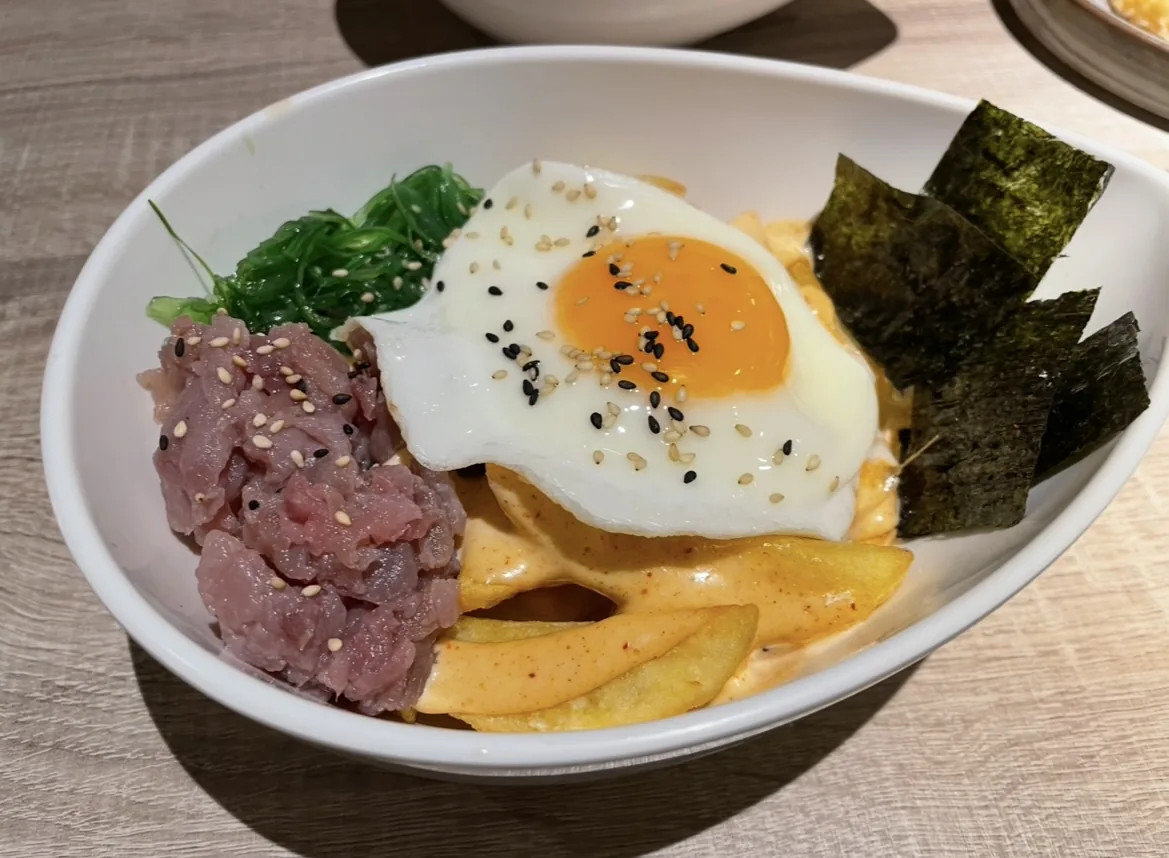 A bowl of tuna tartare with a fried egg and seaweed