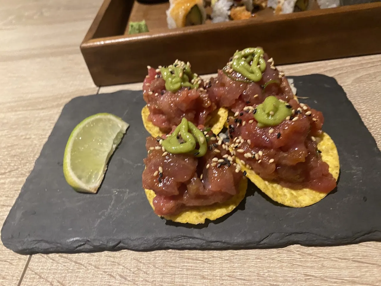 Tuna tostadas topped with avocado on a slate board