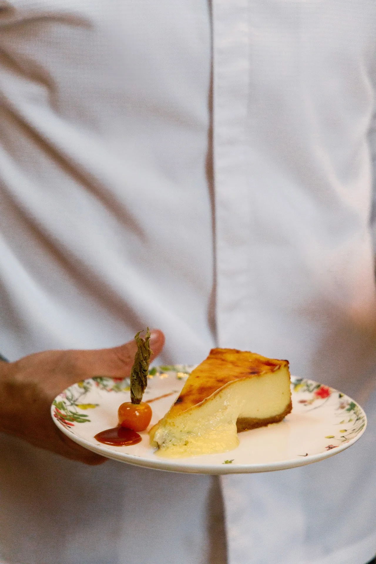 A slice of cheesecake with a red fruit garnish on a plate