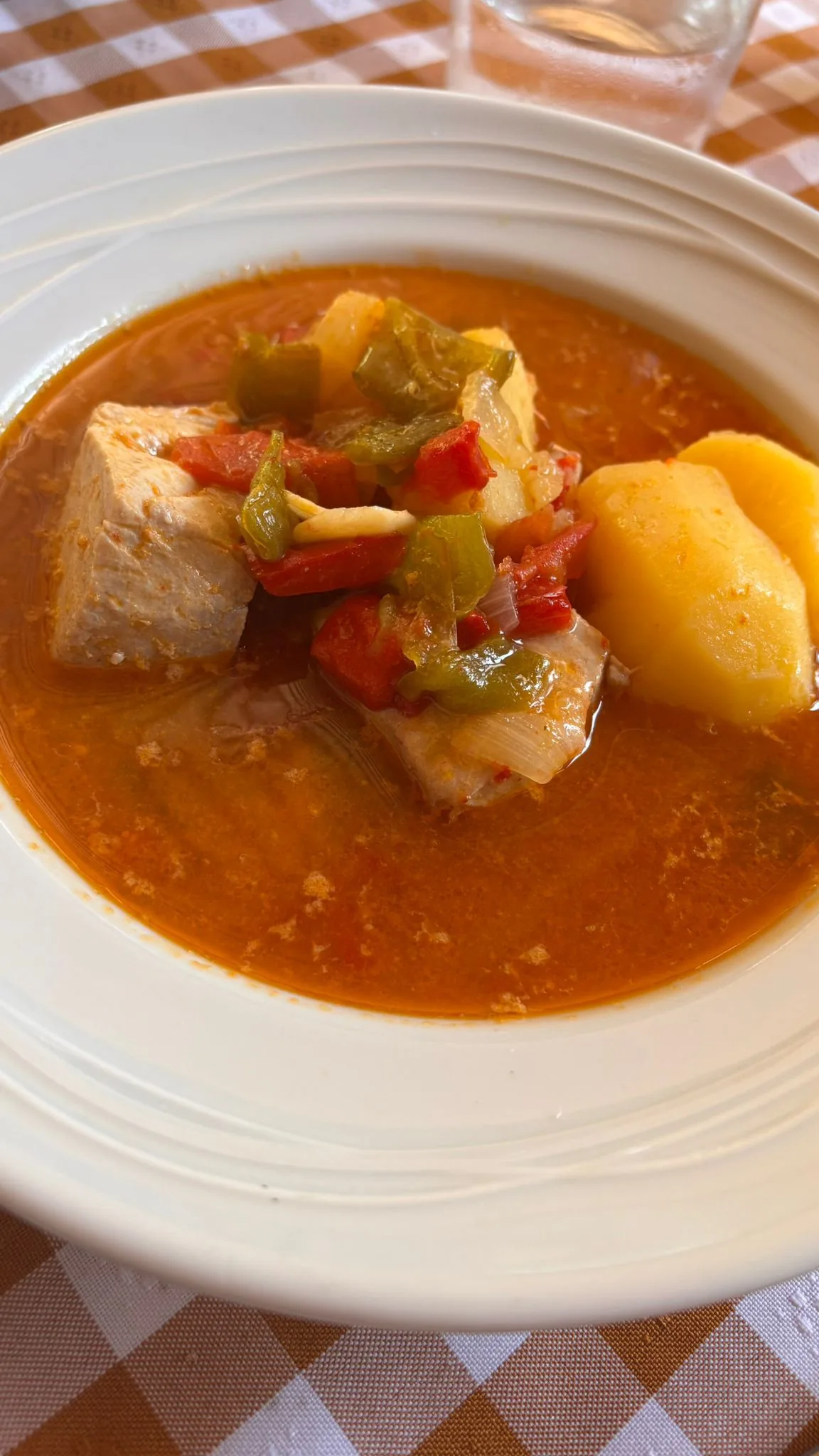 A bowl of fish and potato stew in tomato broth