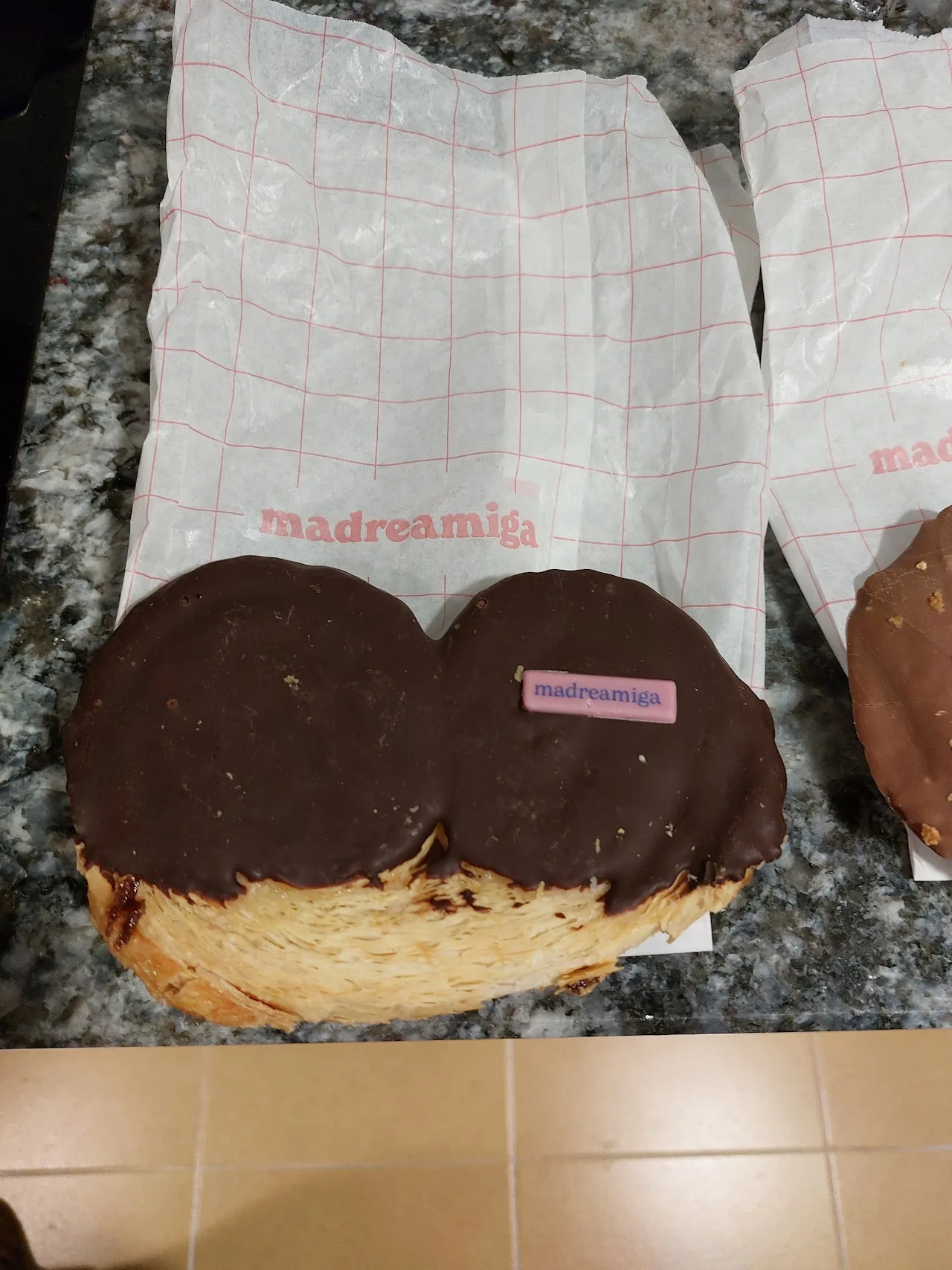 Two chocolate-glazed cream-filled donuts on wrapping paper