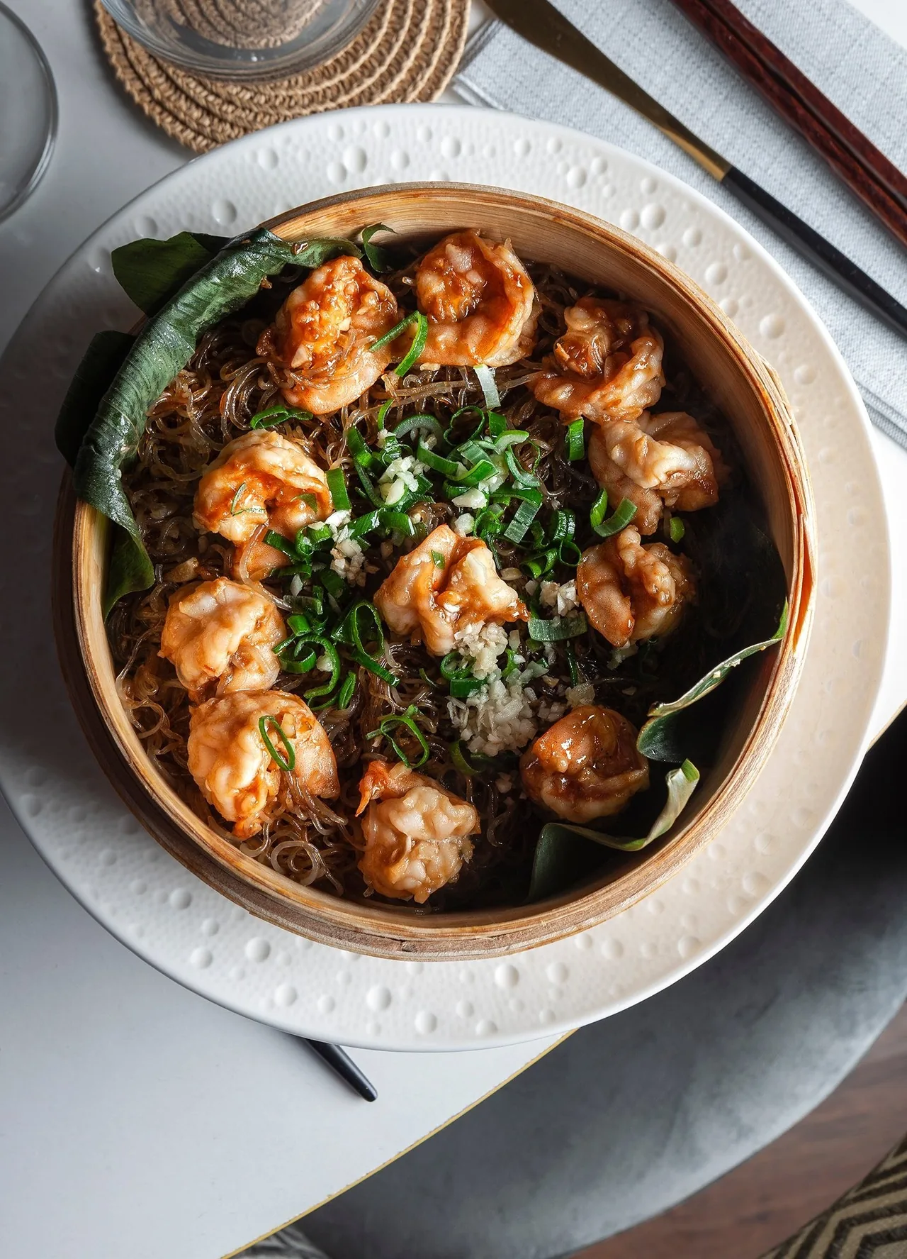 A bowl of prawns on glass noodles with herbs