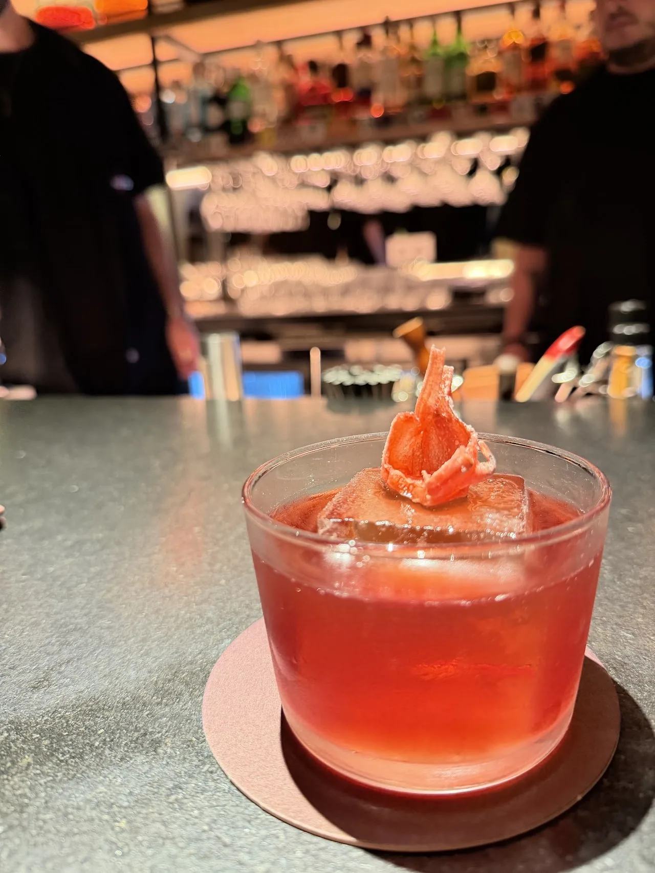 An orange cocktail garnished with a shrimp skewer