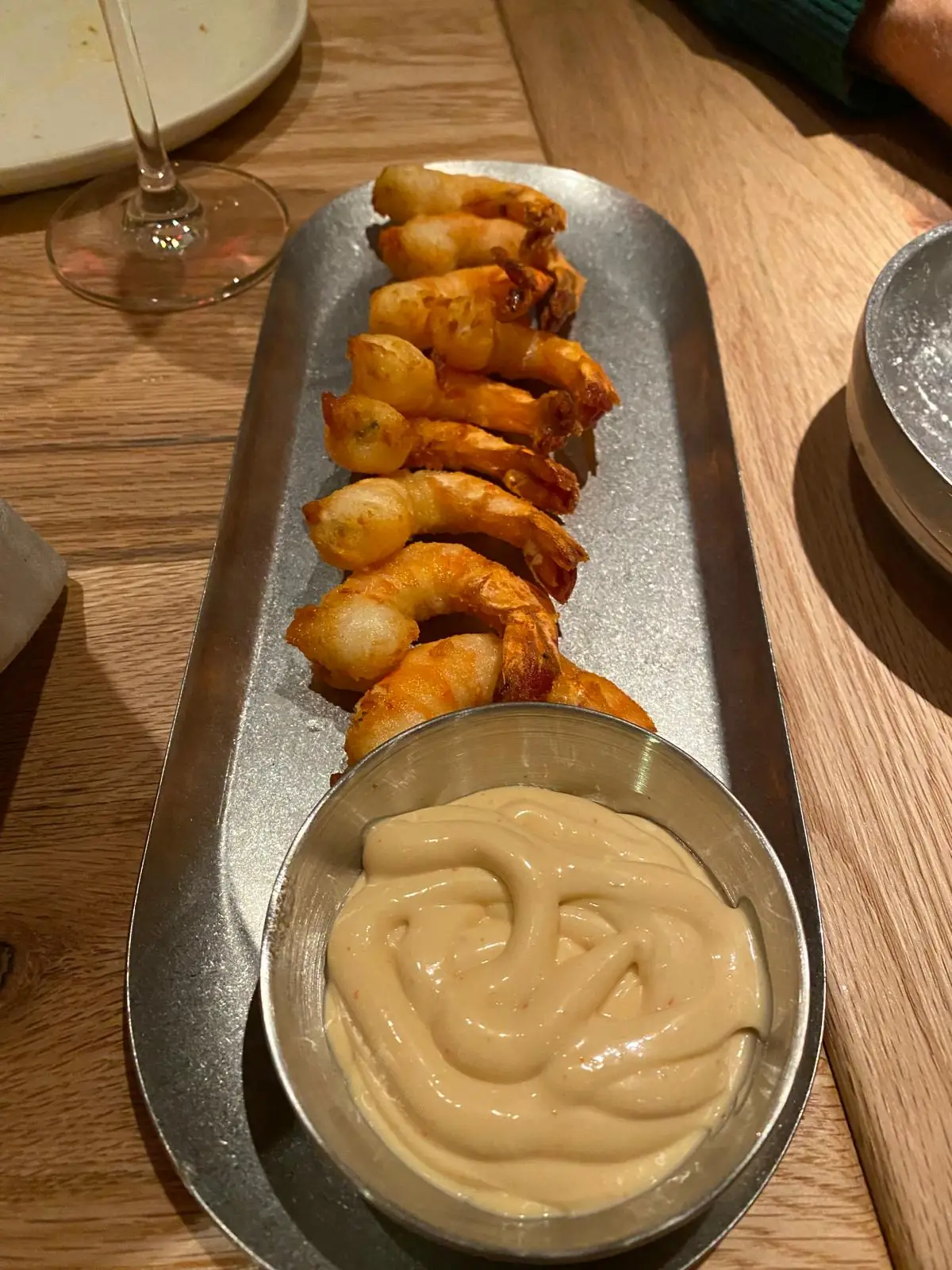 Crispy fried prawn rolls on a metal tray with a pot of aioli
