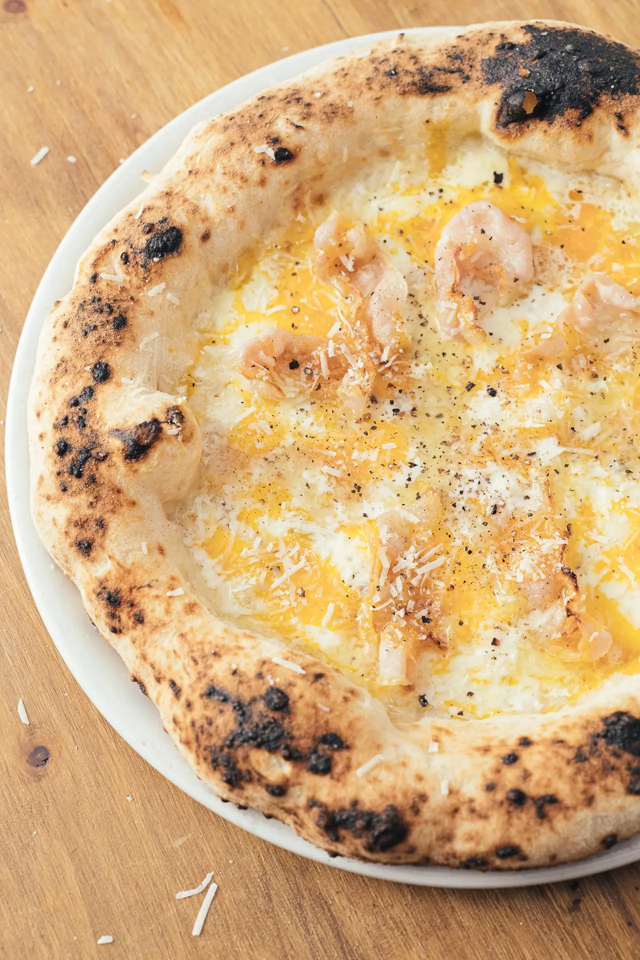 Wood-fired white pizza topped with melted cheese, shrimp, and cracked black pepper at MAMA