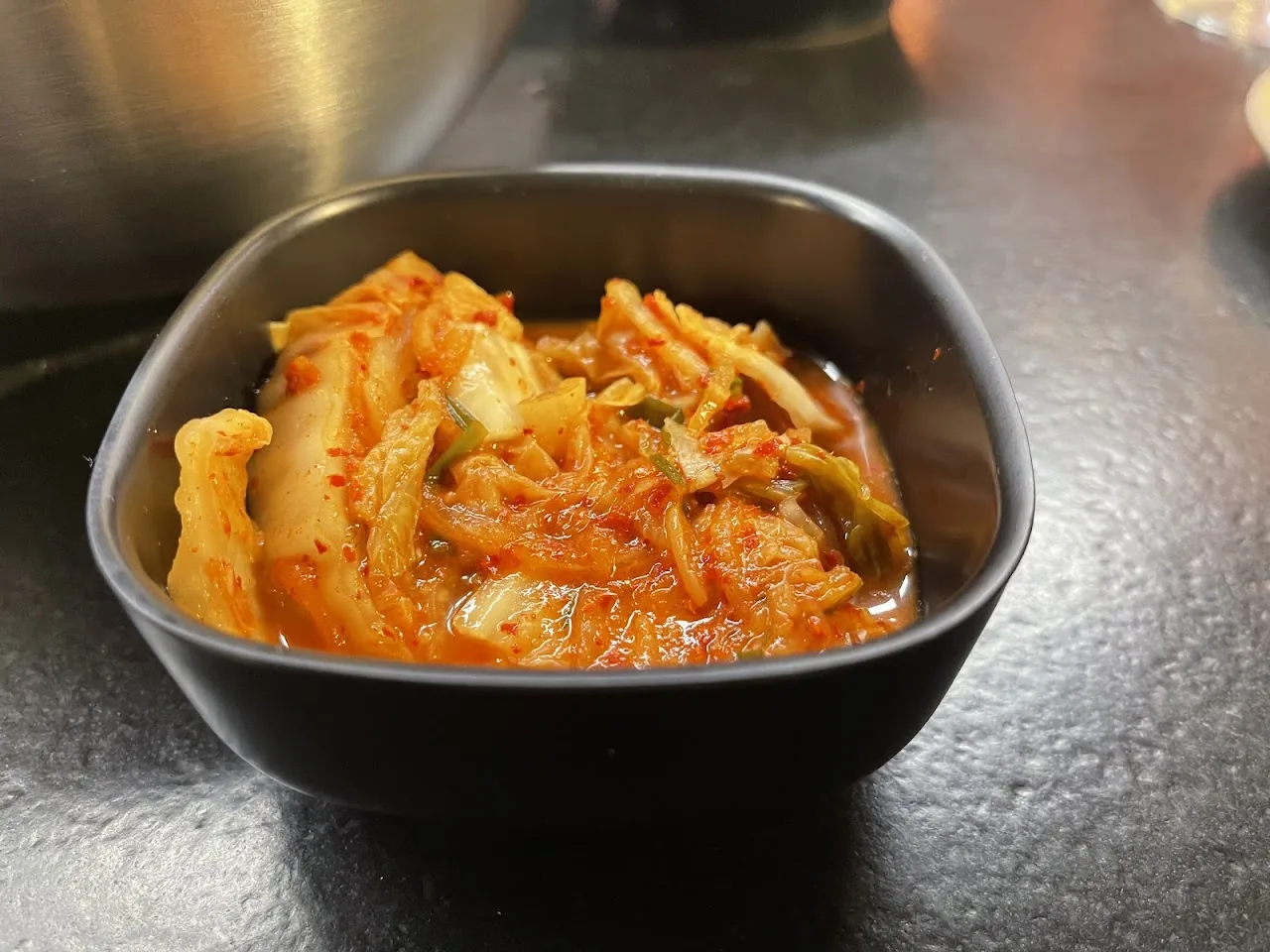 A bowl of kimchi with scallions