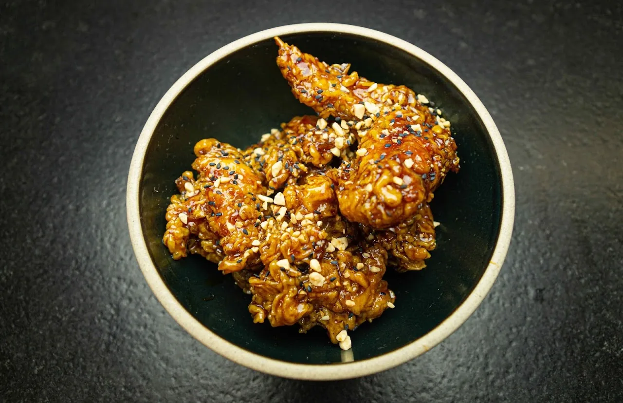 A bowl of glazed Korean fried chicken bites with sesame seeds
