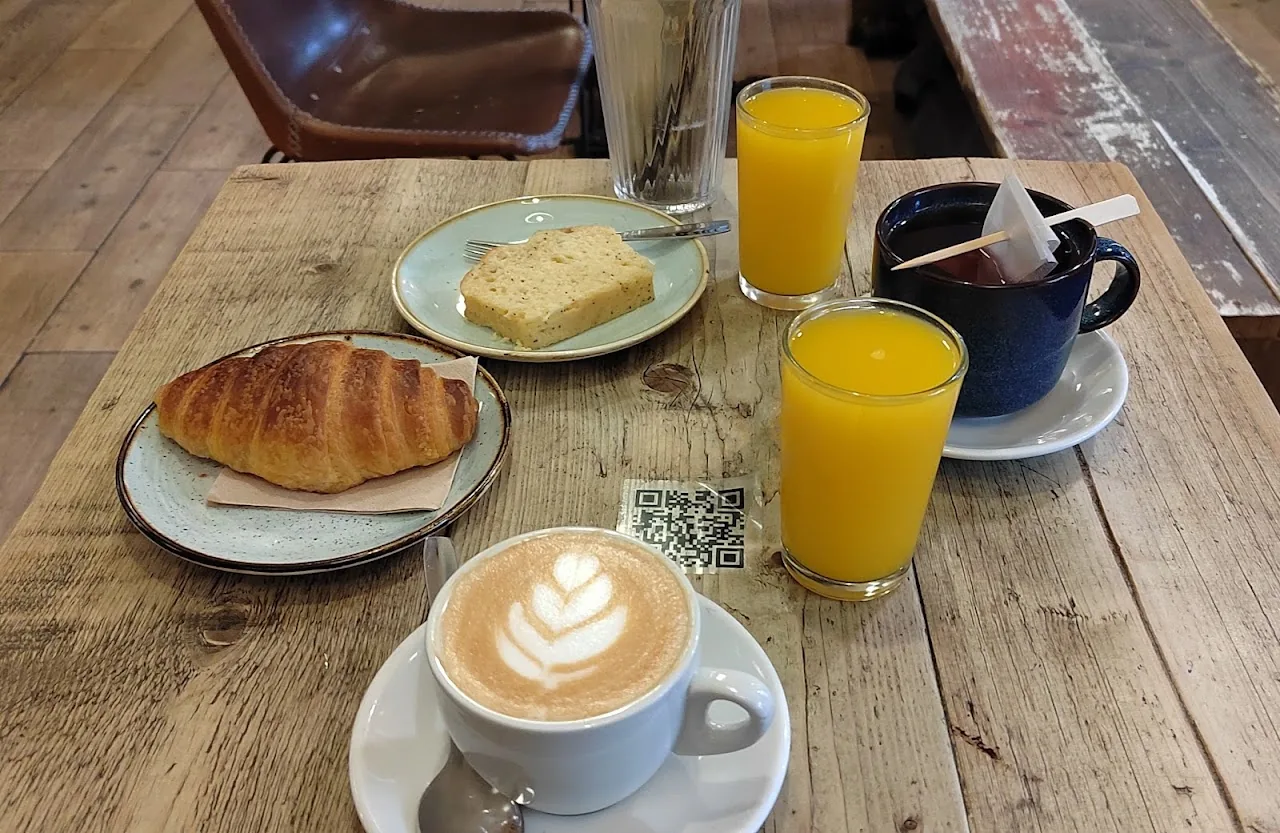 A breakfast spread with a croissant, toast, orange juices and a latte