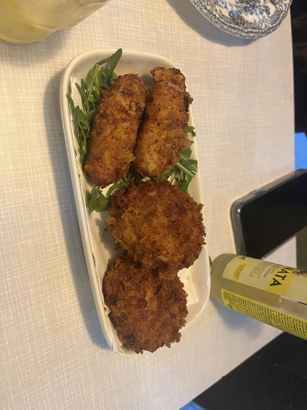 A row of breaded croquettes on a plate with arugula