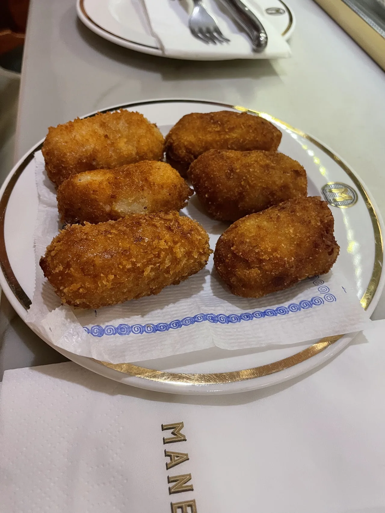 Six golden fried croquetas arranged on a plate
