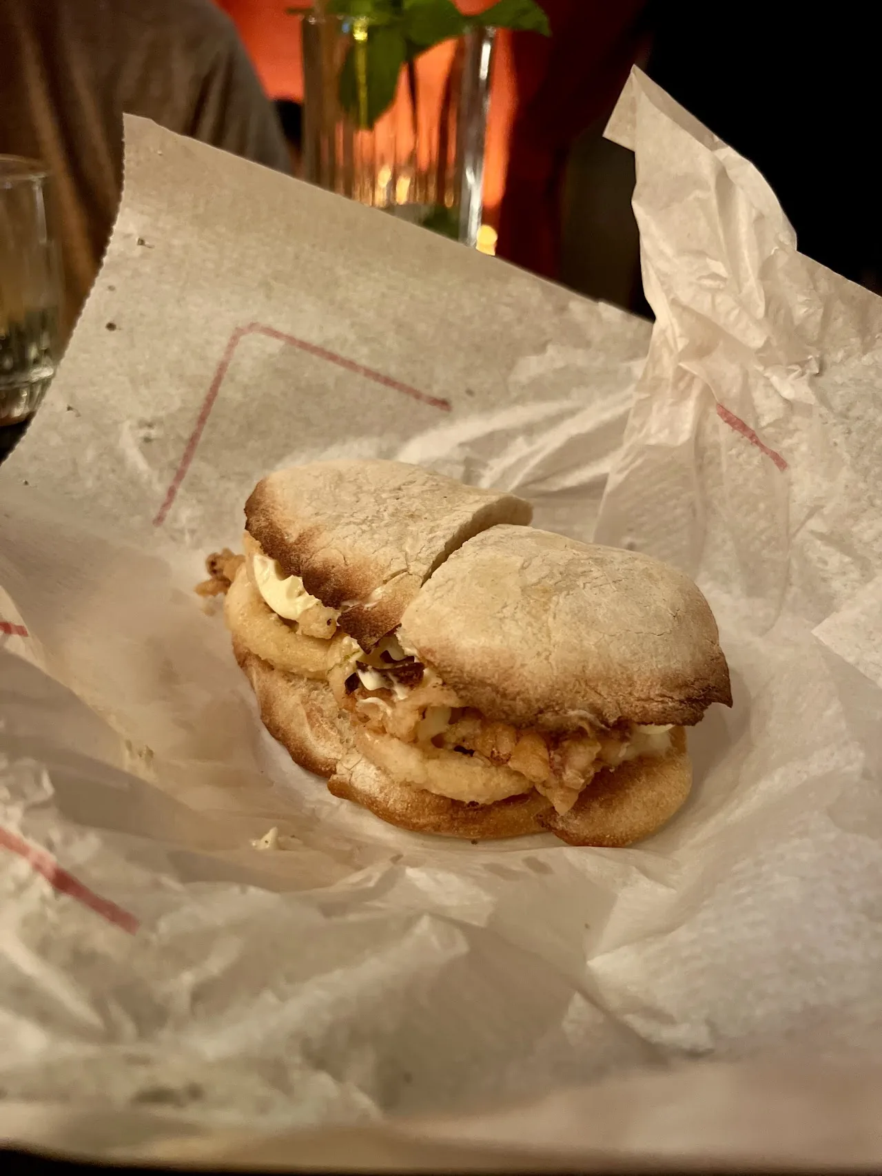 A grilled sandwich filled with meat and cheese, wrapped in paper
