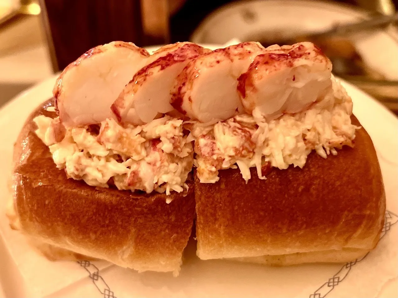 A lobster roll piled with chunks of lobster meat on a plate