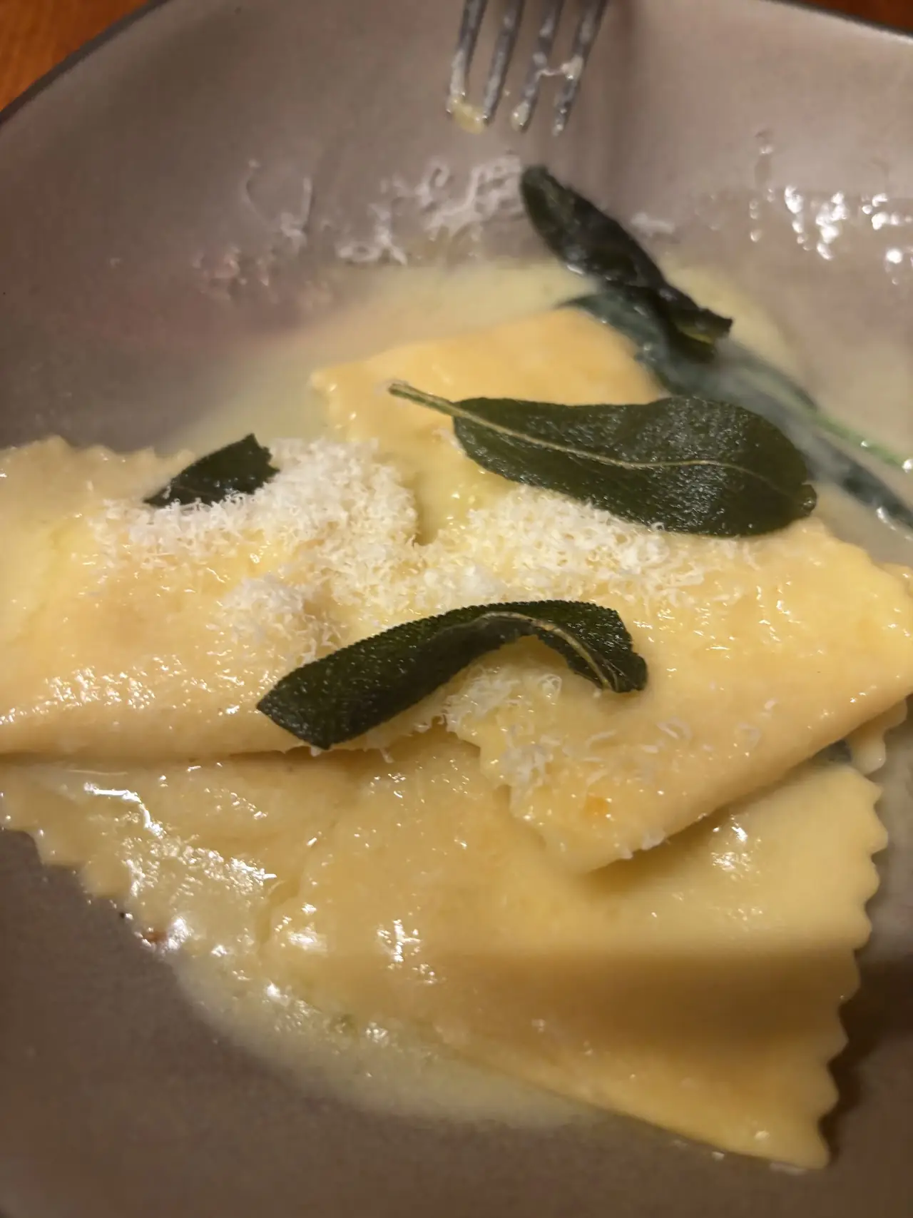 Ravioli in butter sauce topped with crispy sage leaves and grated cheese