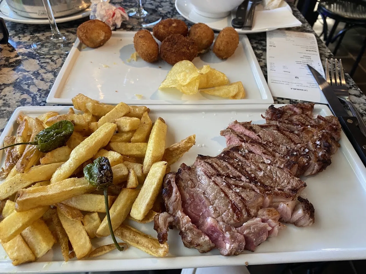 A shared plate of croquettes, French fries, and grilled steak