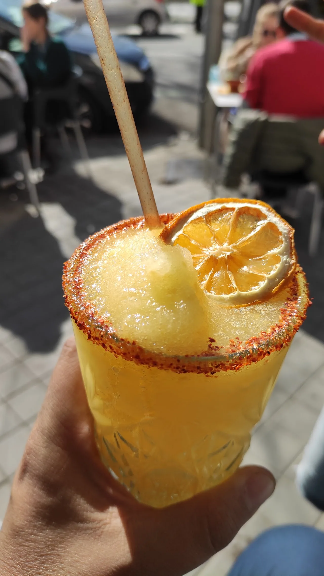 A frozen margarita in a salt-rimmed glass garnished with dried citrus