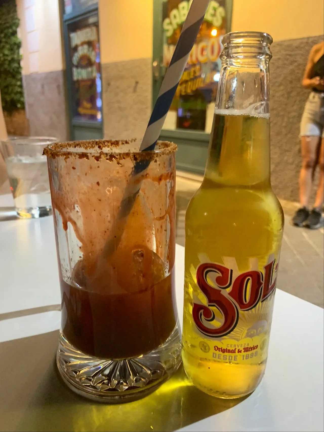 A michelada drink beside a bottle of Sol beer