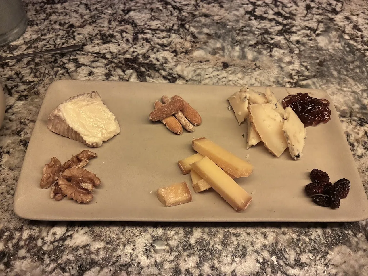 A cheese board with nuts, dried fruit, and honey